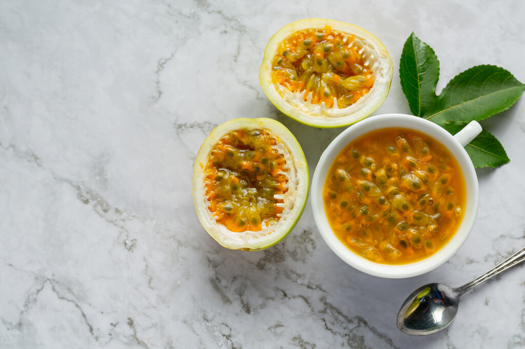 a cup of passion fruit juice and fresh passion fruit cut in half