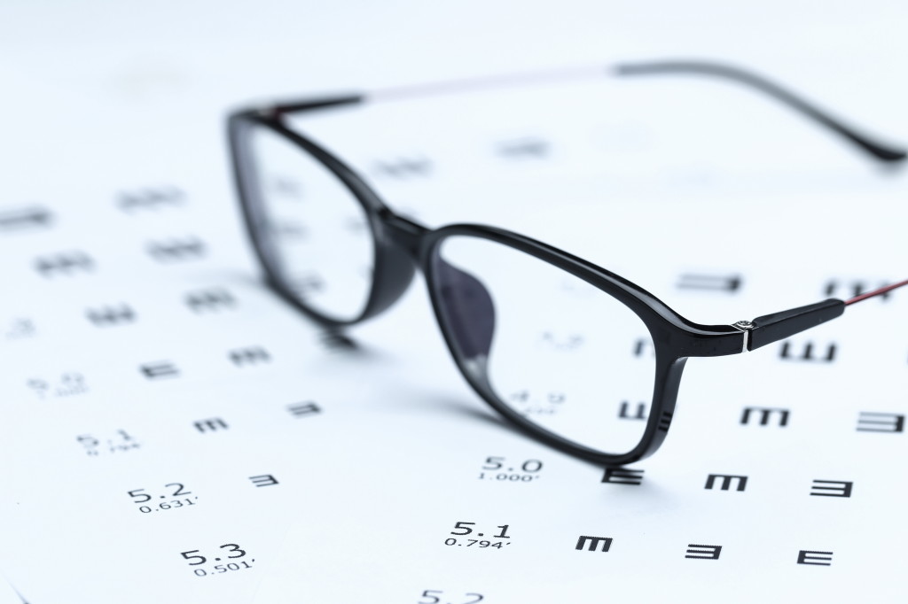 Glasses and eye chart on white background