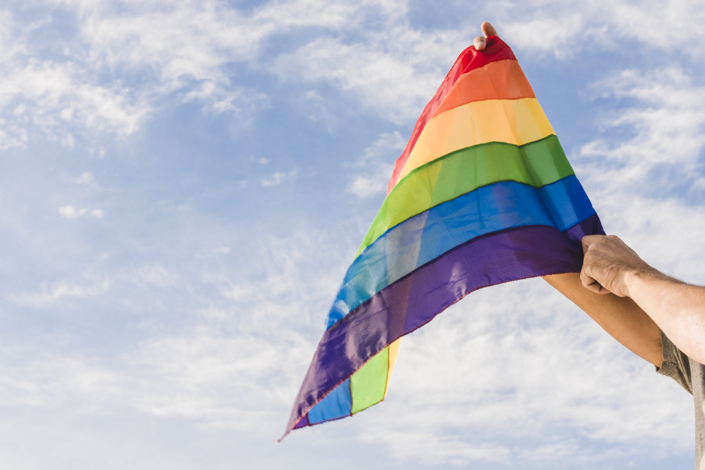 man-with-big-flag-in-lgbt-colors-and-blue-sky