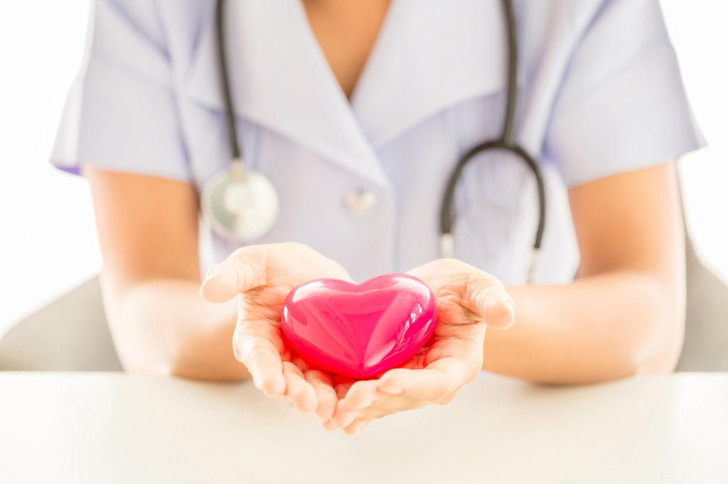 Female nurse with stethoscope holding heart