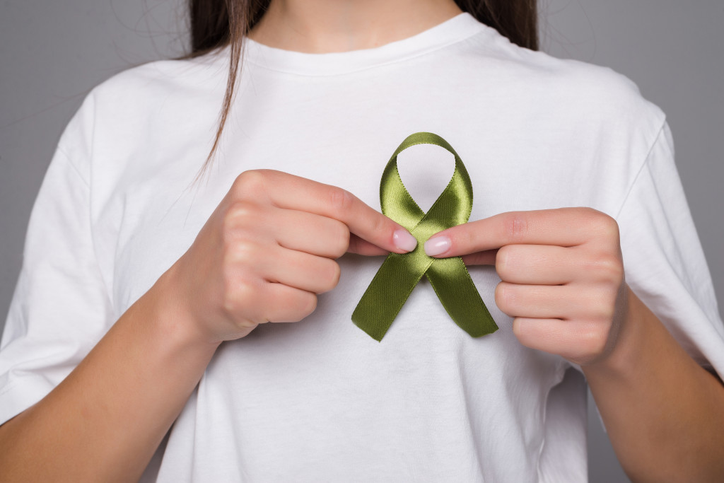 Green ribbon a symbol of cancer isolated on gray background