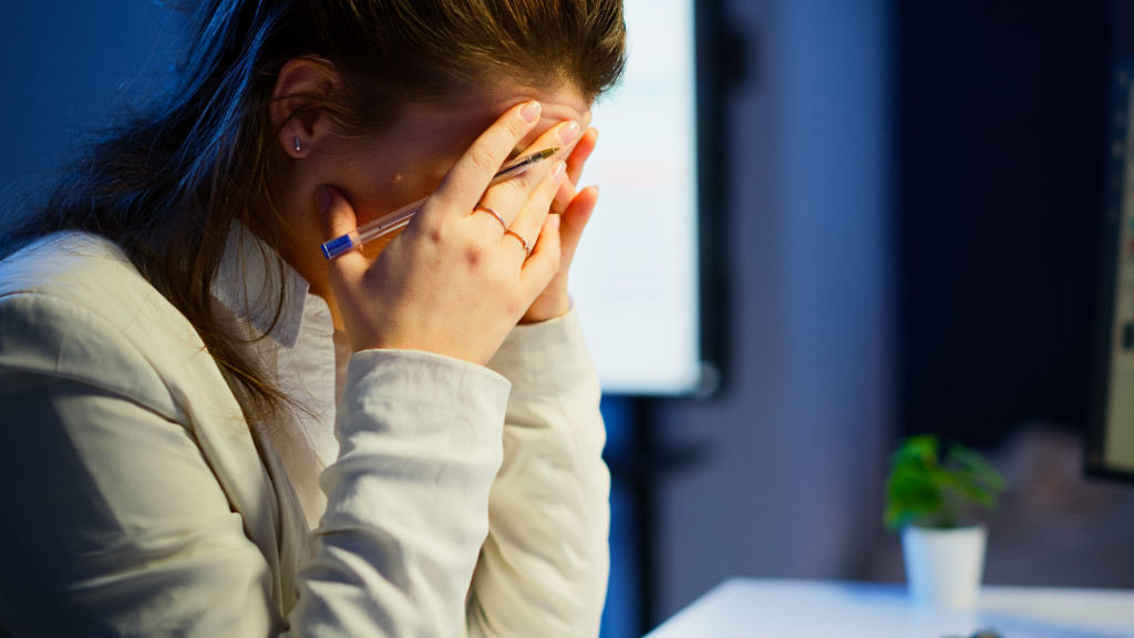 Close up of stressed woman with headache working late at night