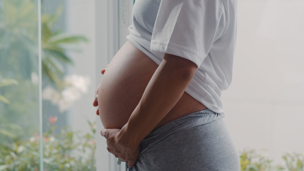 Young Asian Pregnant woman holding her belly talking with her ch