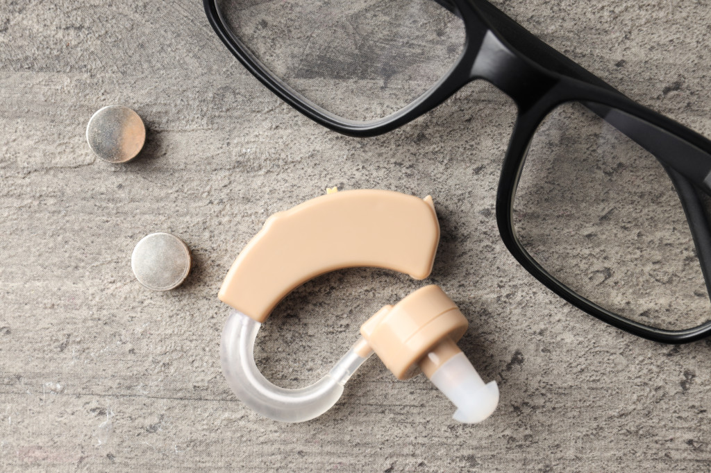 Concept of health care with hearing aid on gray wooden backgroun